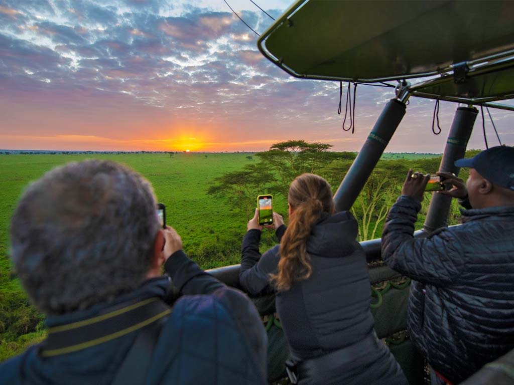 Turistas disfrutando de la impresionante vista del Serengeti durante safaris en globo aerostático.